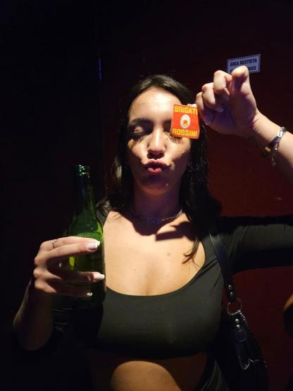 Una ragazza tiene in mano un birra nella mano destra e un adesivo "Brigate Rossini" nella mano sinistra.