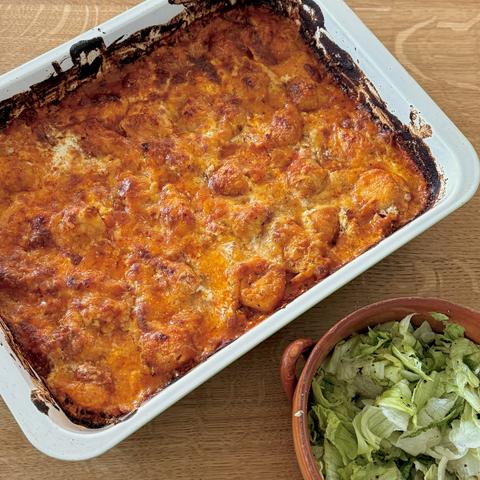 The ready to eat casserole in the oven dish, with a side salad.