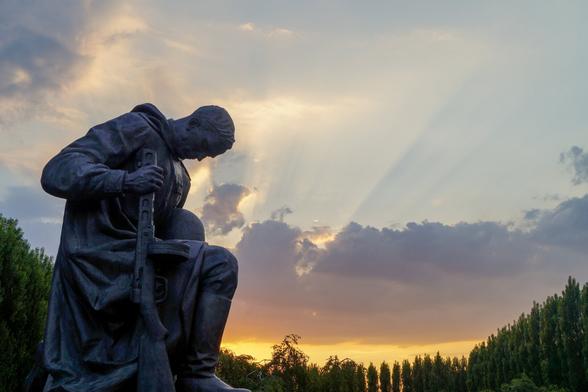 Estatua de un soldado ruso de la Segunda Guerra Mundial en el Monumento Conmemorativo a los Soldados Soviéticos ubicado en Treptower Park (Berlín). Al fondo se ve la puesta del Sol tras la nubes y los árboles.

Statue of a Russian soldier from World War II at the Soviet War Memorial located in Treptower Park, Berlin. In the background you can see the sunset after the clouds and trees.