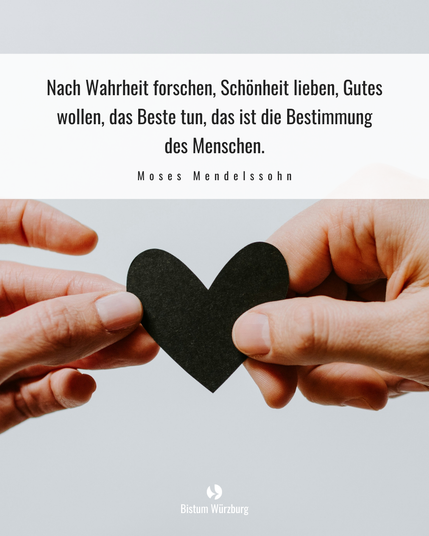 Zwei Hände halten ein schwarzes Herz. Darüber steht ein Zitat von Moses Mendelssohn: "Nach Wahrheit forschen, Schönheit lieben, Gutes wollen, das Beste tun, das ist die Bestimmung des Menschen."