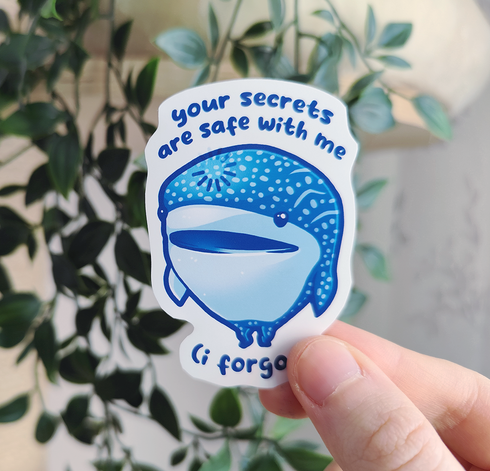 Hand holding up a sticker of a silly shark standing on his fin titled "your secrets are safe with me (i forgot)"