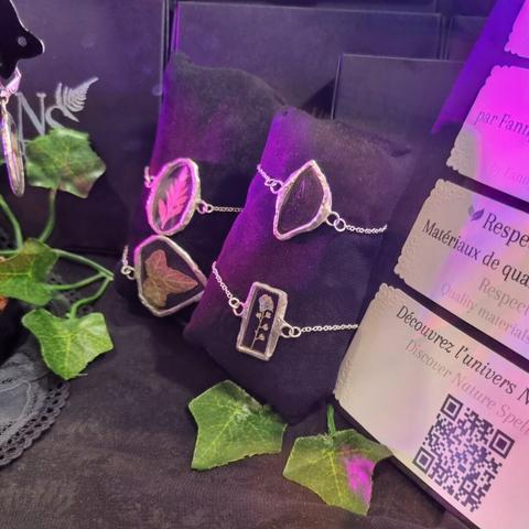 English Closeup on a store window full of jewelry: bracelets made of stained glass and real pressed plants and insects wings.
Français Gros plan sur une vitrine de magasin pleine de bijoux : bracelets en vitrail et avec de vraies plantes et ailes d'insectes pressées.