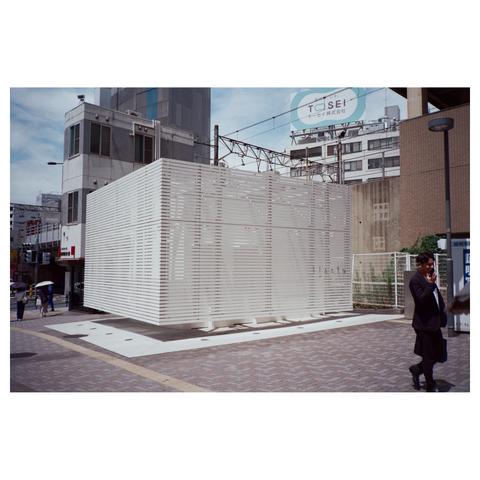 The toilet building at the railway station is a white cube made from horizontally aligned boards.
