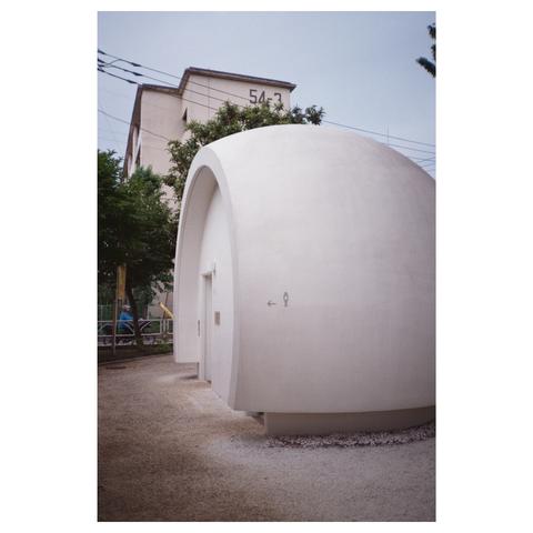 The building looks like a concrete sphere, with a cut-off front. This is where the entrance door is located.