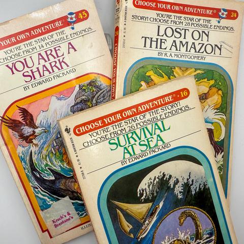 A collection of three "Choose Your Own Adventure" books, featuring titles: "You Are a Shark," "Lost on the Amazon," and "Survival at Sea." Each book highlights its interactive storytelling format, with illustrations on their covers.