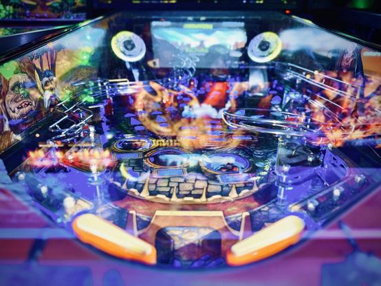 A colorful, "Labyrinth"-themed pinball machine lights up brightly next to other pinball machines on either side.