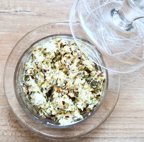 Die fertige Kapernbutter in einer Glasschale, der Deckel liegt daneben