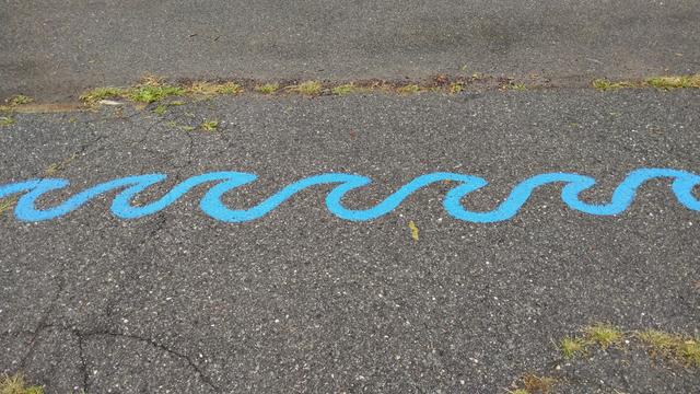 A painting of blue saves on a driveway.