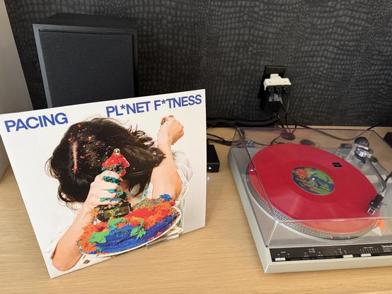 Picture of the album art of Pl*net F*tness by Pacing next to a record player.