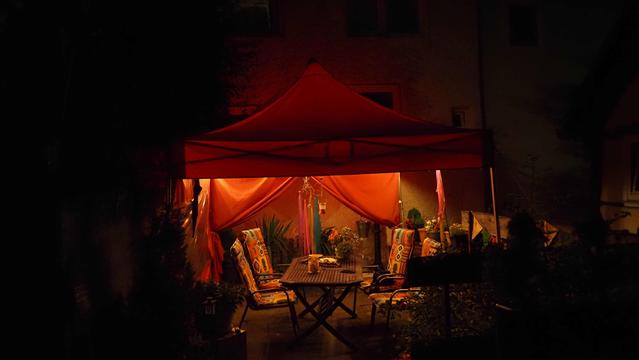 Roter Pavillon im Dunkeln , Beleuchtet, Stühle mit bunten Stuhlkissen