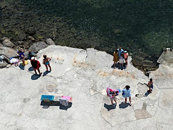 Foto van badgasten op rotsplateau aan zee (van boven gezien)