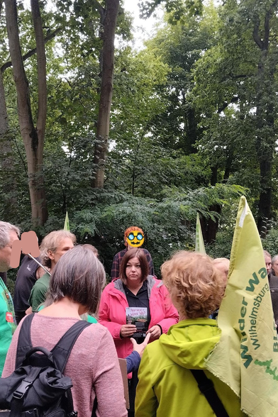 Foto der Demo, inmitten einer Traube an Menschen steht Fegebank mit einem WiWa Flyer in der Hand