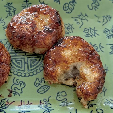 The fried and caramelised daikon fritters on a serving plate, now in an appetising brown golden colour.