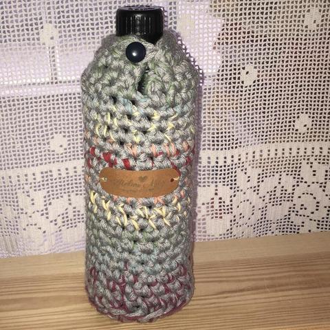 Wiederverwendbare Glasflasche mit gehäkeltem Thermoschutz in Grau und Pastellregenbogenfarben