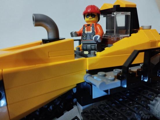 Figura de la conductora del bulldozer de pié en su cabina.