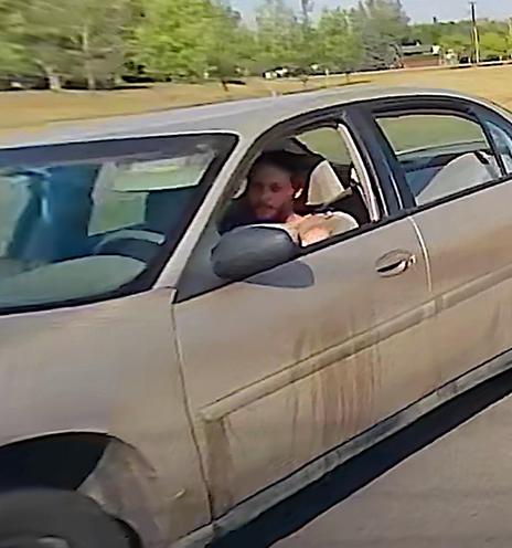 A still frame from the dashcam video, showing the asshole road-rager in question, as well as some lovely detail of his POS Chevy Malibu in genuine Stewed Dirt colour, and running on its winter steel wheels (and presumably bald winter tires) in the middle of August.

He wears a wifebeater shirt, because of course he wears a wifebeater shirt.