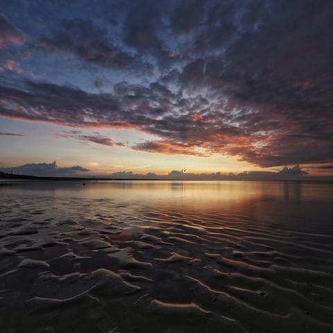 rosa Wolken über dem Meer am Abendhimmel davor der gerippte Strand bei Ebbe