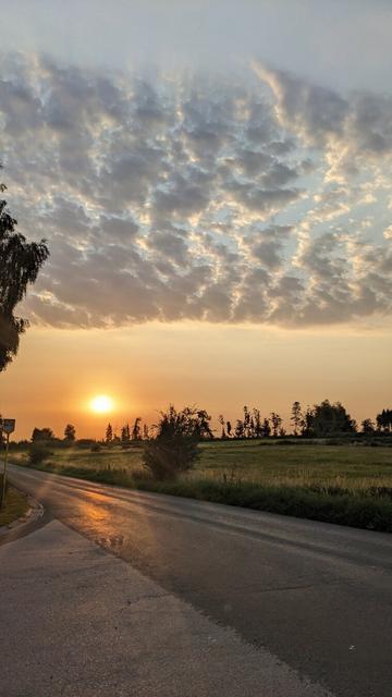 Sunrise and textured clouds réflection on the road