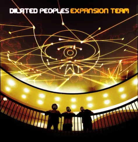 Album cover for Expansion Team by Dilated Peoples. The artwork features a glowing futuristic ceiling with bright yellow-orange light trails crisscrossing like a global network, forming an abstract eye in the center. A faint map of the world is visible behind the lines, giving the impression of worldwide connectivity. At the bottom of the image, the three members of Dilated Peoples stand silhouetted against a curved balcony, looking up at the illuminated display above them. The title DILATED PEOPLES EXPANSION TEAM appears at the top in bold white and orange lettering, emphasizing a sense of vision, movement, and global reach.