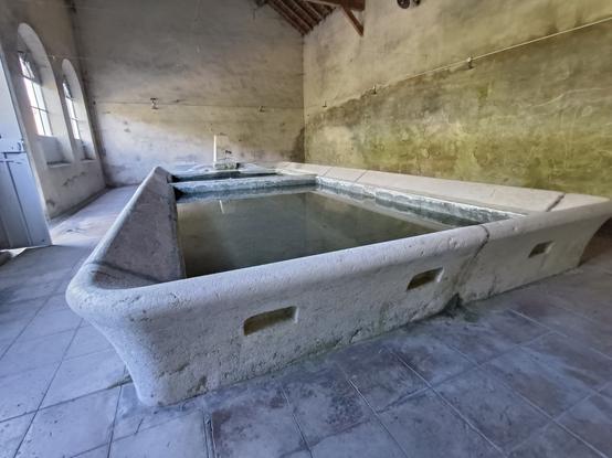 4 photos numériques couleur de différents formats, avec une vue en grand angle d'un grand lavoir rectangulaire en pierre claire et rempli d'eau. Le robinet est de l'autre côté. Le lavoir est abrité dans un bâtiment avec des grandes fenêtres arrondies.