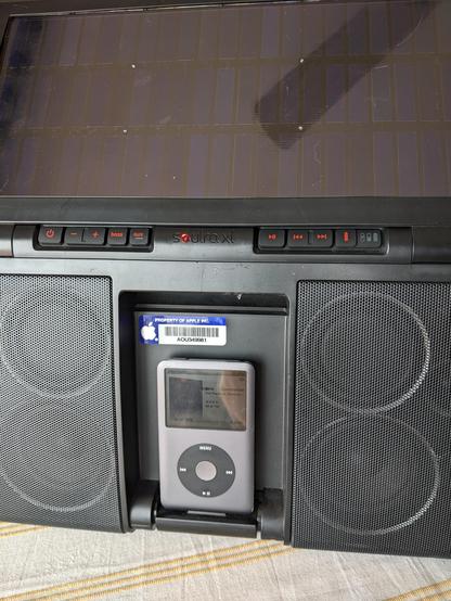 A soutraxl iPod dock, with an iPod playing a podcast. The apple property logo is still attached