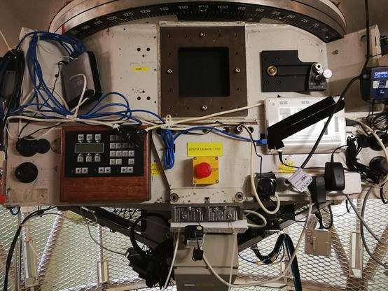 Photo of a large piece of vaguely industrial looking machinery, with lots of electronic devices from different eras attached to it. One of these is a white Asus Eee PC netbook, closed and attached to the structure with velcro.