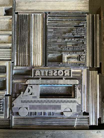 Sur le marbre de la presse Grafix, les caractères mobiles s’assemblent pour créer le camion de Rosetta et le Colophon