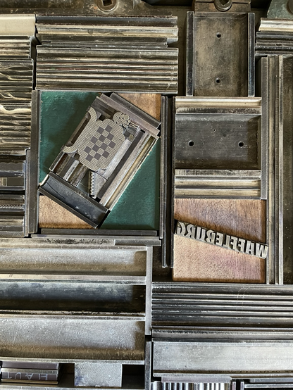 Sur le marbre de la presse Grafix, les caractères mobiles s’assemblent pour créer le ballon en forme de chien et waffleburg