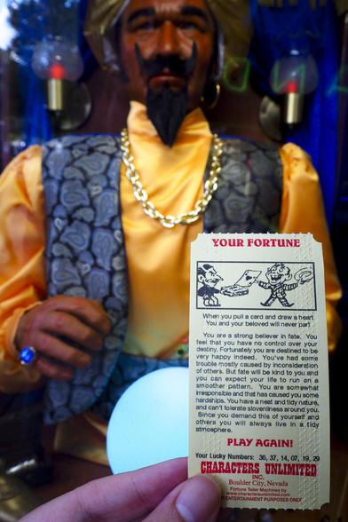 A yellow card containing a fortune being held up in front of a Zoltar fortune teller machine.  The fortune reads:

When you pull a card and draw a heart You and your beloved will never part.

You are a strong believer in fate. You feel that you have no control over your destiny. Fortunately you are destined to be very happy indeed. You've had some trouble mostly caused by inconsideration of others. But fate will be kind to you and you can expect your life to run on a smoother pattern. You are somewhat irresponsible and that has caused you some hardships. You have a neat and tidy nature, and can't tolerate slovenliness around you. Since you demand this of yourself and others you will always live in a tidy atmosphere.

Your lucky numbers: 36, 37, 14, 07, 19, 29