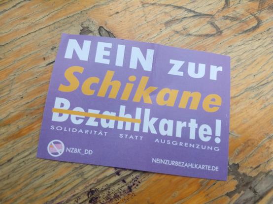 Ein Sticker auf dem folgendes steht: Nein zur Schikane Bezahl (das Wort ist durchgestrichen) Karte! Solidarität statt Ausgrenzung