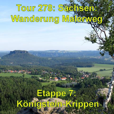 Blick von einem Sandsteinfelsen auf eine ländliche Szenerie im Licht der aufgehenden Sonne. Vorne links im Bild sieht man die Kante eines Sandsteinfelsens und darüber ein paar Äste. Unterhalb breitet sich ein Dorf mit roten Dächern umgeben von grünen Wiesen aus. Im mittleren Bildbereich erkennt man ein größeres, bewaldetes Plateau und dahinter sanft ansteigende, bewaldete Hügel. Der Himmel ist hellblau und klar.