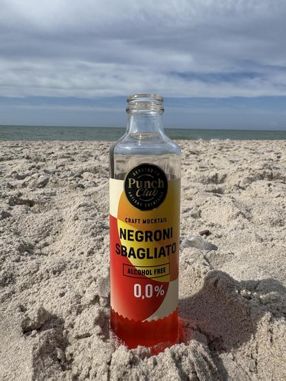 Eine kleine Glasflasche am Strand im Sand stehend, im Hintergrund die Nordsee und leicht bewölkter Himmel:
Punch Club
CRAFT MOCKTAIL
NEGRONI SBAGLIATO
ALCOHOL FREE 0,0%