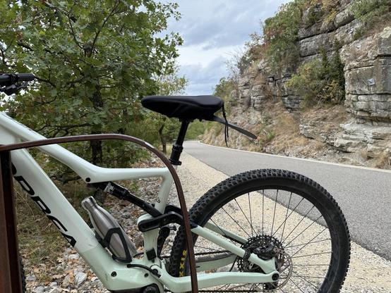 Hinterrad eines orbea rise eMTB an einem Radweg mit Felsen im Hintergrund.