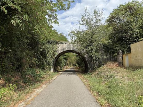 Stück einer stillgelegten Bahntrasse, die jetzt ein Radweg mit einer bogenförmigen Brücke