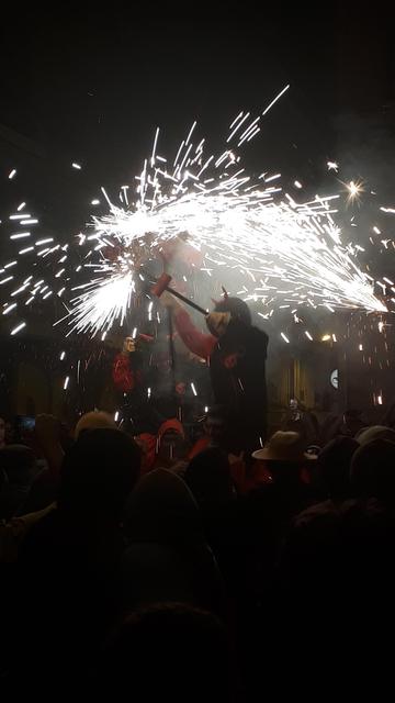 correfoc, czyli ludzie przebrani za diabły biegną/chodzą/tańczą z fajerwerkami. Na zdjęciu widok sponad tłumu, ktoś wziął taką osobę "na barana" dlatego widać ją w miarę wyraźnie. Ma w ręku kij na którego końcu są fajerwerki, może nim obracać i wtedy iskry lecą na wszystkie strony.