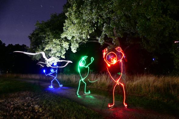 Auf einem nächtlichen, aber dennoch einigermaßen erleuchteten Parkweg tanzen drei aus Licht gezeichnete Strichmännchen. Das hinterste, in blau, steht breitbreinig da und hebt die Arme nach links in die Höhe. Das mittlere, in grün, tut dasselbe, aber seitenverkehrt. Das vorderste, in rot, wiederum tut es dem blauen gleich. Neben dem hell angeleuchteten Baum, der von rechts über den Weg ragt, ist der Sternenhimmel zu sehen. Insgesamt ergibt sich so eine ulkig-einladende, freundliche Szenerie.