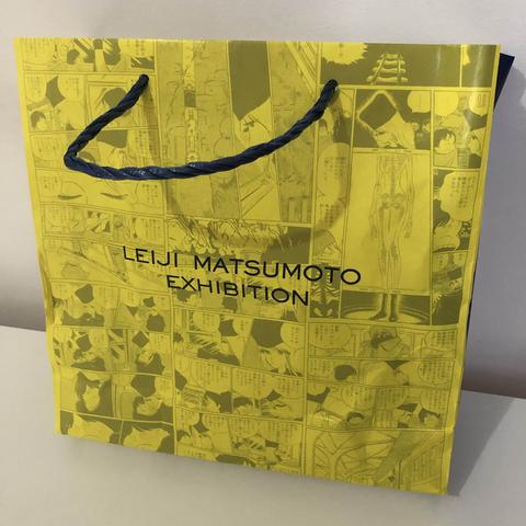 Sac en papier jaune. Le texte imprimé indique "Leiji Matsumoto Exhibition".