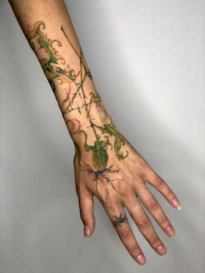 Tattoo of a colorful thistles on an arm and hand