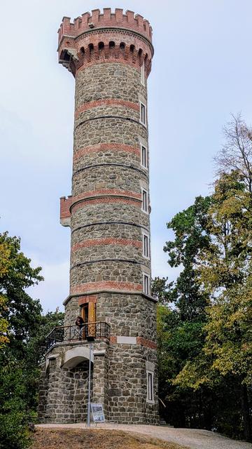 Kamenná rozhledna s červenými kruhy z cihel.