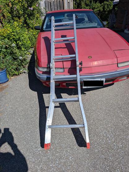 My photo of a scaffold ladder leaning against my red Buick Reatta.