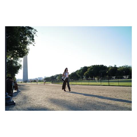 Photo of a woman walking past the Washington Monument at the National Mall in D.C.