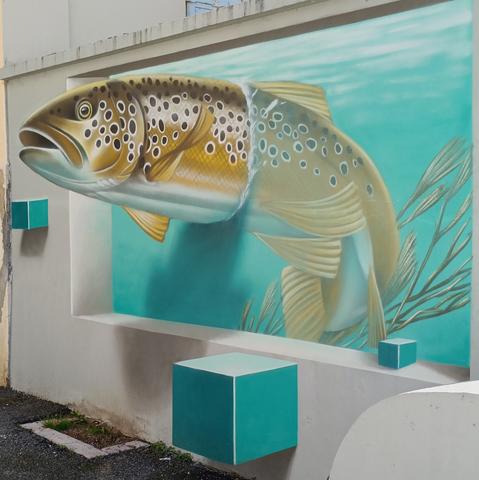 Une truite beige et des cubes bleus semblent surgir de l'eau et du mur.