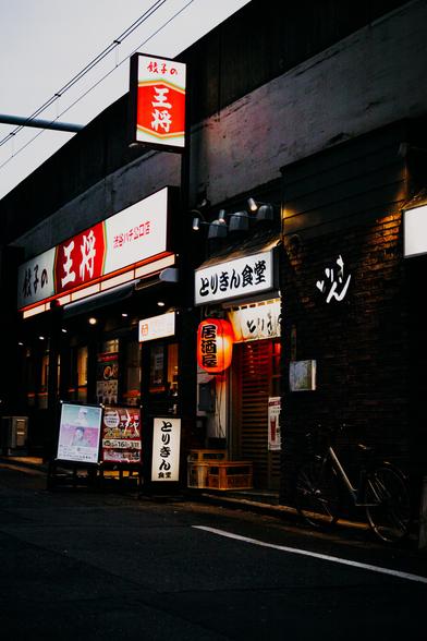 photo of a side street in tokyo with a restaurant and its bright advertisement signs