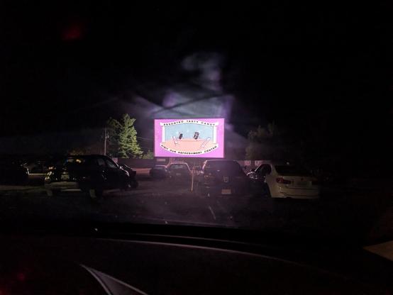 A view through a somewhat messy windshield, looking at an intermission animation at a drive-in