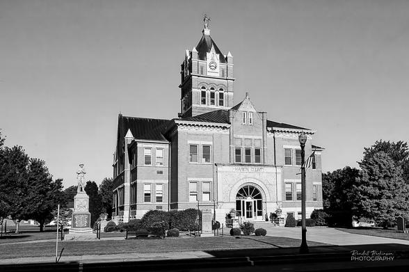 A view of the Marion County, Missouri Courthouse, a two story building with a central tower, on a bright, sunny morning.