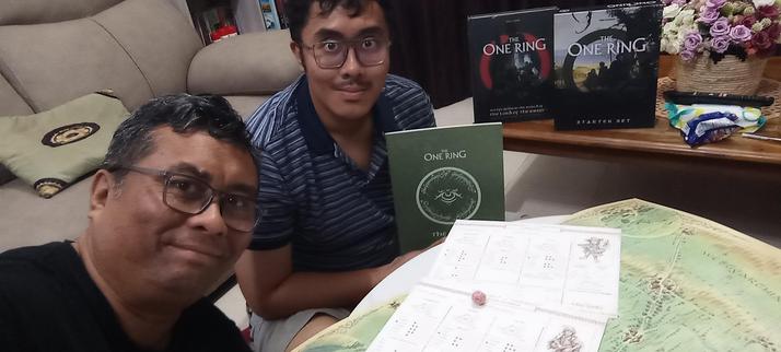 My son and I with The One Ring 2E Starter Set books and map on the table.