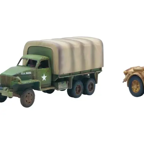 A green and brown camouflaged American Studebaker truck is positioned on the left, featuring a covered cargo area and a white star insignia on its side. Next to it, on the right, is a tan Autoblinda AB41 armored car, showcasing a rounded body and a turret, with a slightly weathered appearance. Both vehicles are detailed models suitable for tabletop gaming, reflecting their historical designs from WWII.