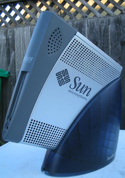 A SunRay 1G terminal from Sun Microsystems, image taken outside in front of a wood fence that is weathered and showing character.