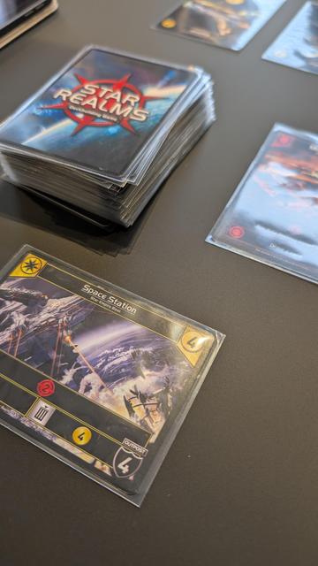 Yellow Space Station outpost card next to a deck of face-down Star Realms cards.
