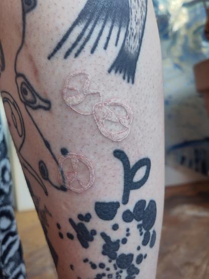 White ink abstract tattoo on a lower leg
